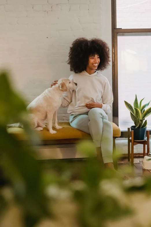 a woman sits on her bed with a dog looking on