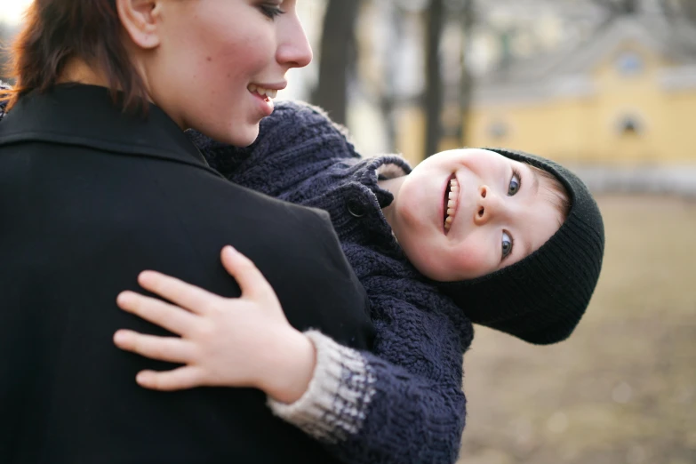 woman with child wrapped in coat looking to the side