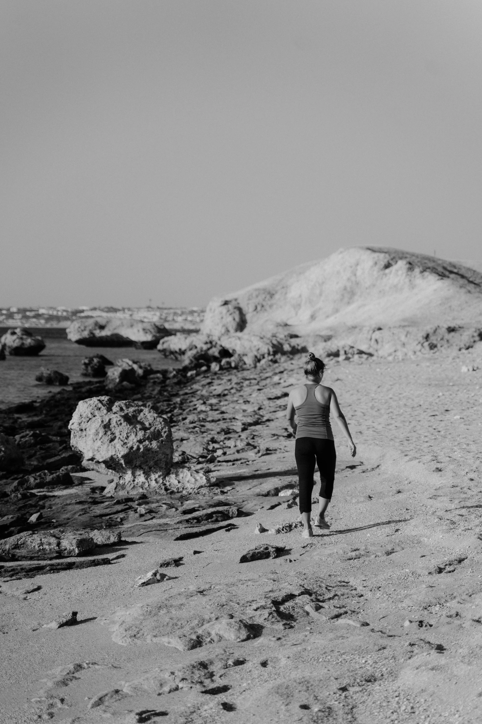 woman in gray running along the beach near the ocean