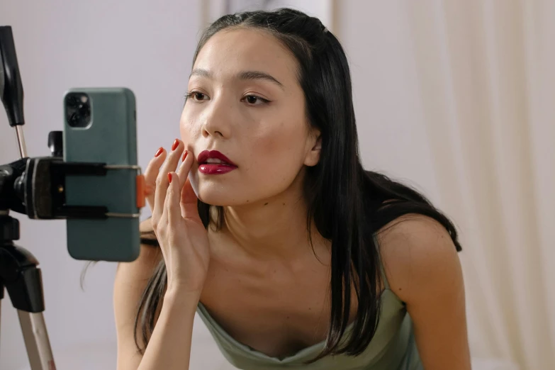 woman applying makeup while looking in a mirror