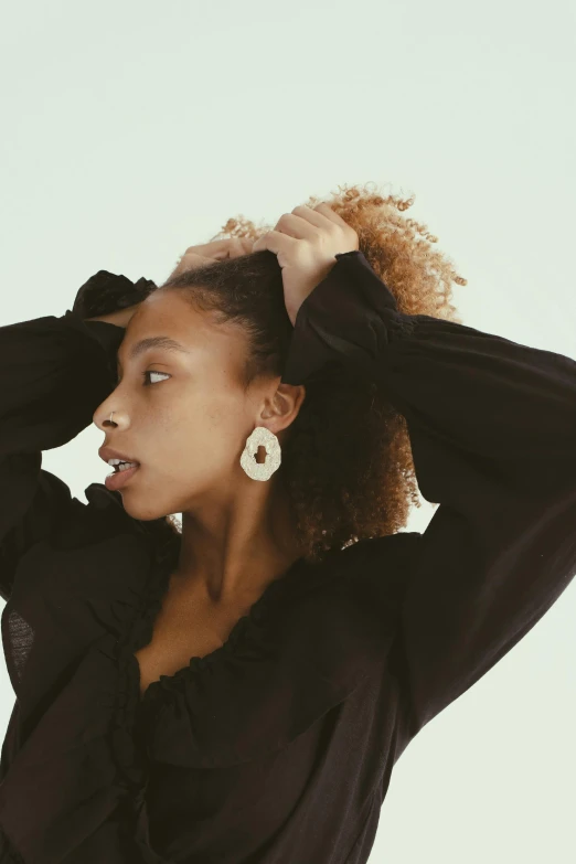 a woman with curly hair standing and wearing a black top