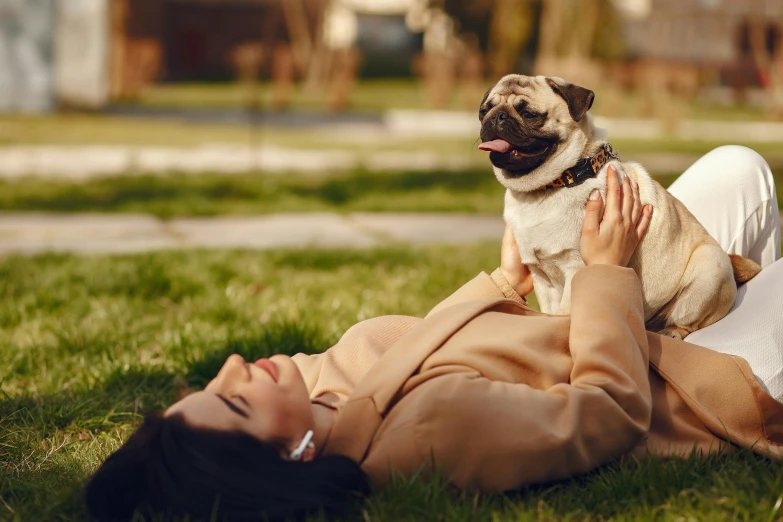 a young woman lies on the ground next to a pug