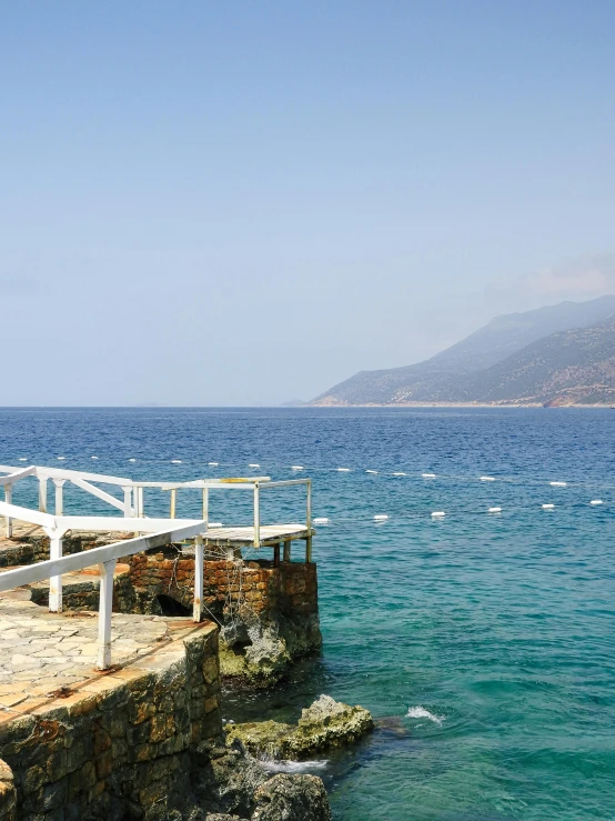 an empty pier near the water with a mountain range in the background