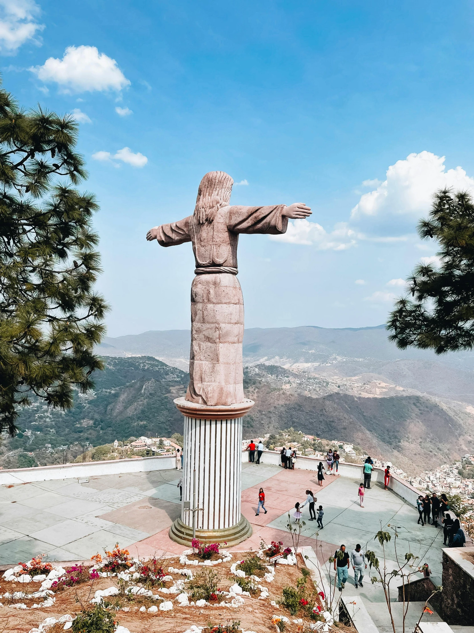 a statue of christ overlooks a landscaped mountain