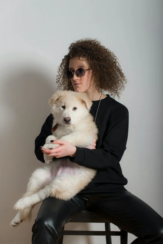 a woman is holding her white fluffy dog