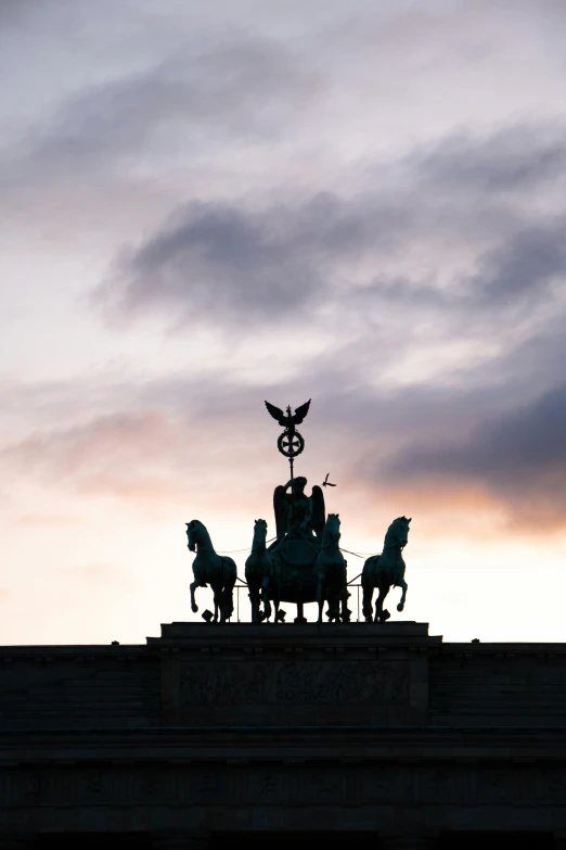 silhouetted statues of horses and riders stand against the dark purple sky