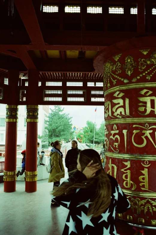 a woman stands in front of a tall pillar