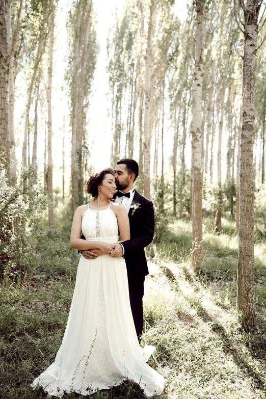 a newly married couple is standing in the forest