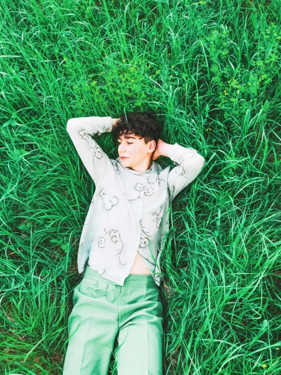 a man laying on his back in the middle of a grass field