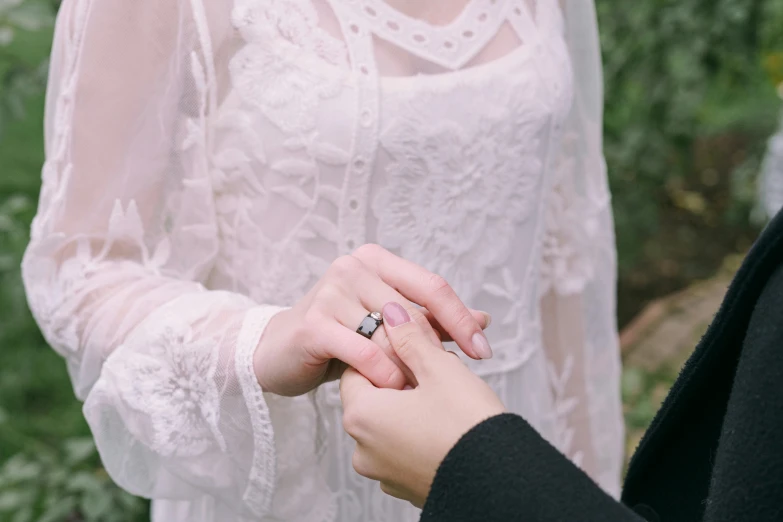 an older woman places a ring on the grooms finger