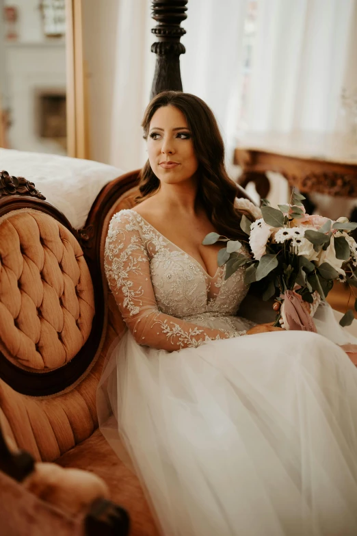 a bride poses in her wedding dress on the arm chair