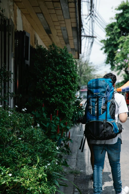 man carrying backpack walking through a city street