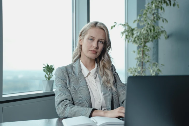 a woman sitting at a desk with a laptop and book