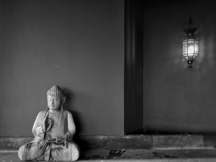 a statue sitting on top of a stone bench in front of a lamp