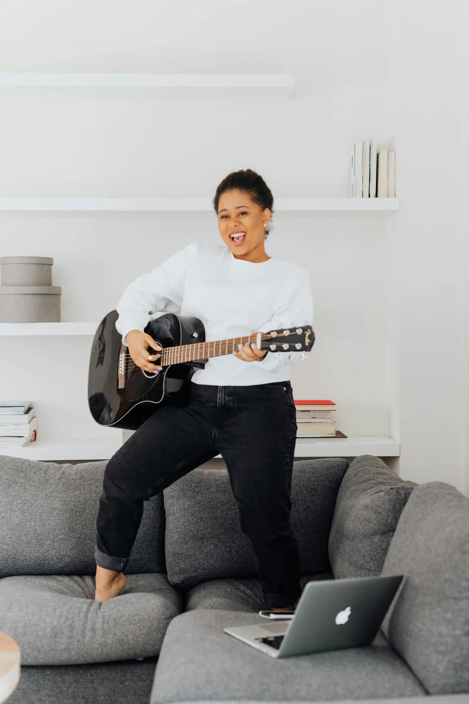 a smiling woman with an acoustic guitar and laptop