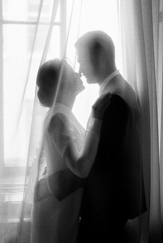 a couple emcing near window in silhouette