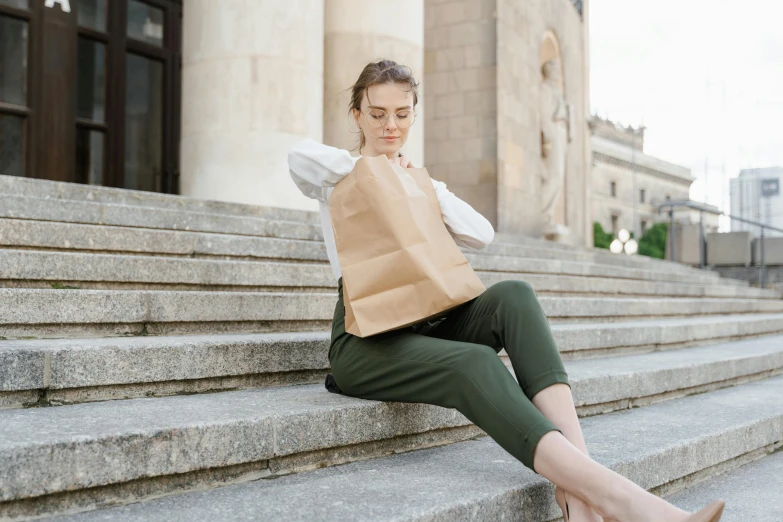 woman in business attire on a stairway looking at paper bag