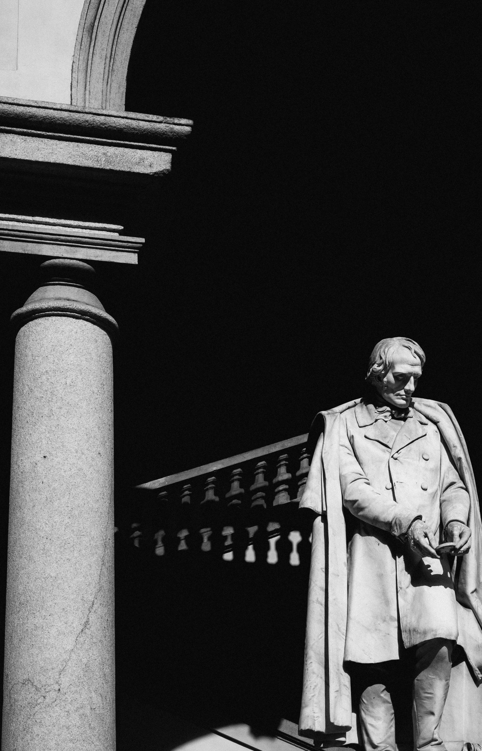 a statue is in front of a column on a sidewalk