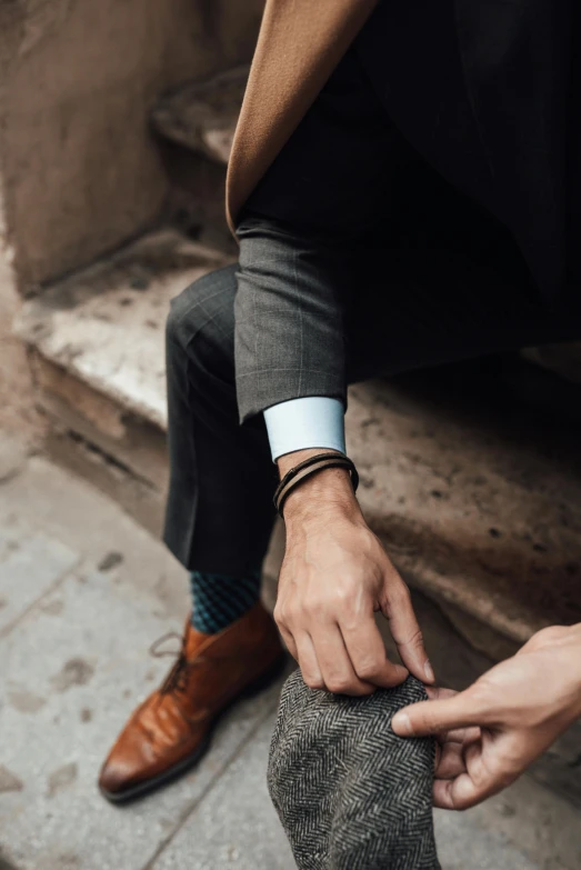 a man in a suit adjusting a tie on the other side of his shoe