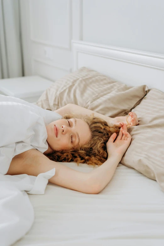 a young woman laying in bed with white sheets