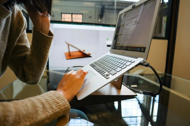 a woman is sitting at a desk while using her laptop computer