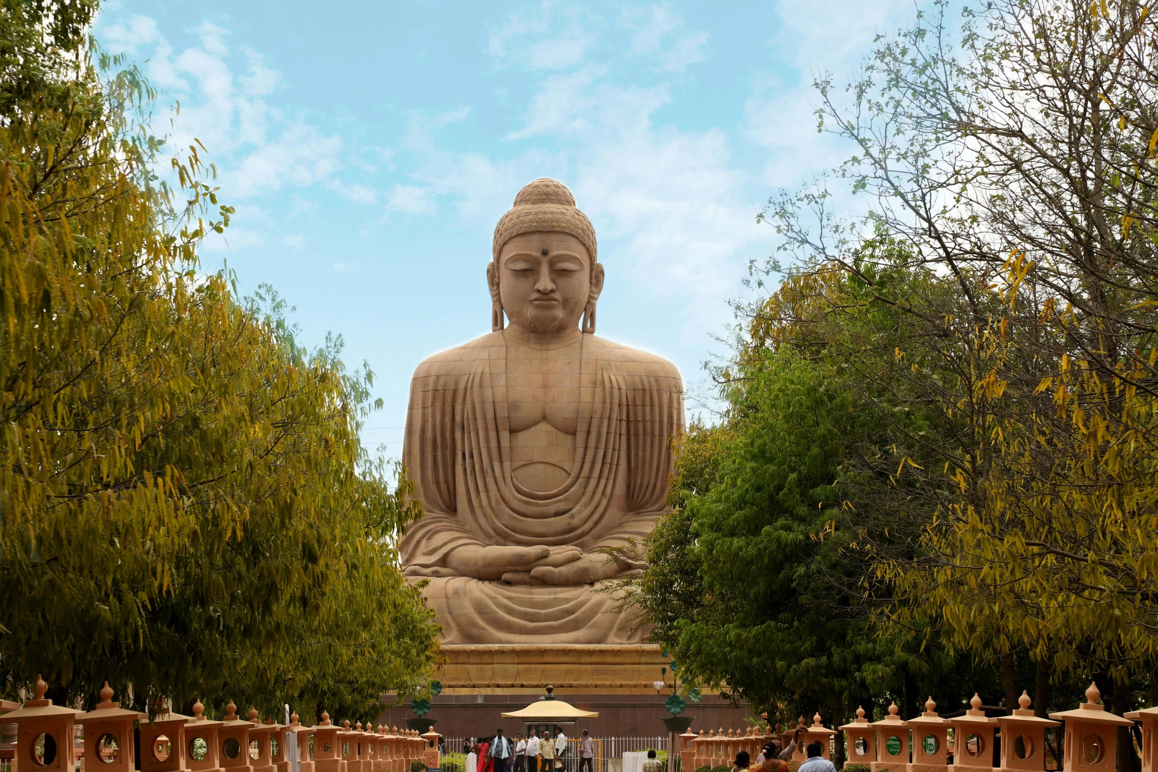 large statue in middle of garden with wooden fence around it