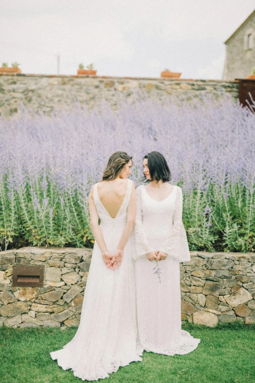 two women wearing white are standing together in the grass