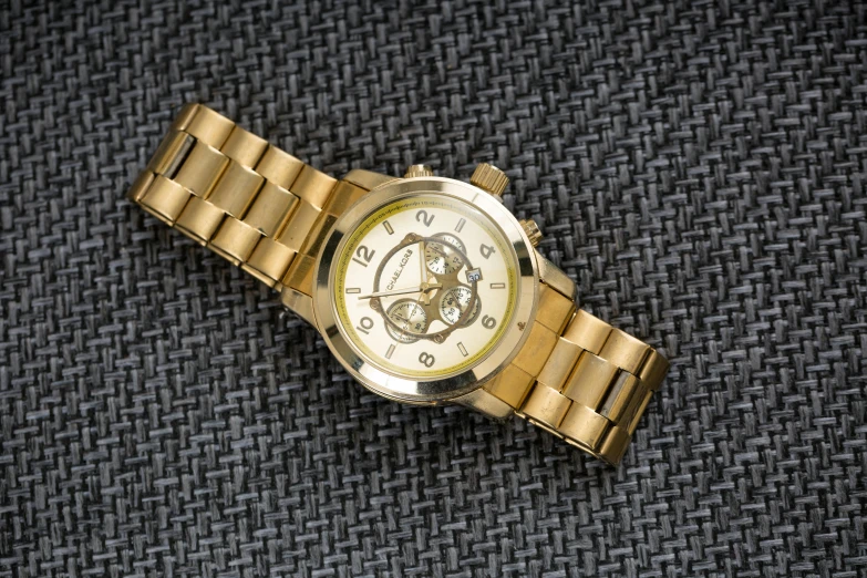 a gold wristwatch on a grey fabric