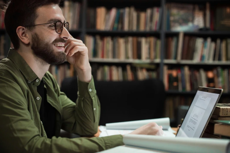 the man is smiling while looking at his laptop