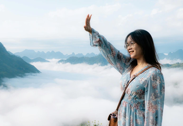 the woman is holding up her hand while looking into the sky