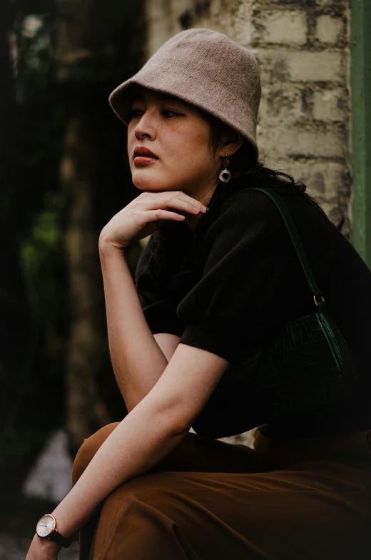 a woman sitting on the ground with a handbag around her neck