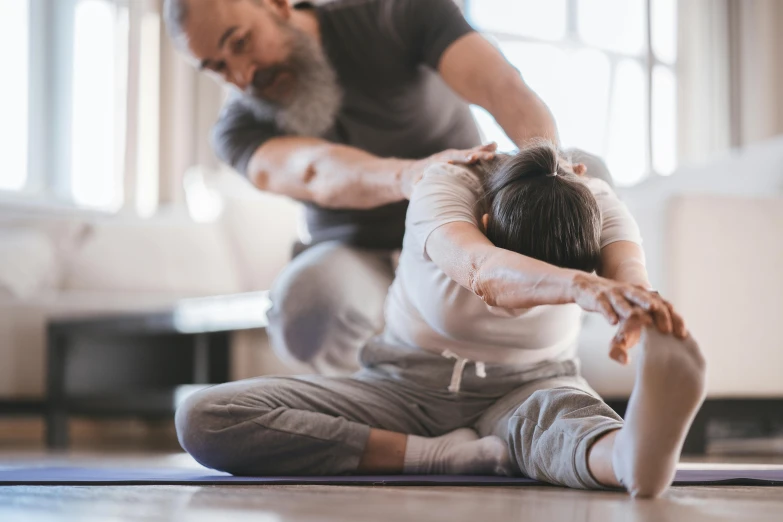 man performing aerial exercise on carpet while woman stands nearby