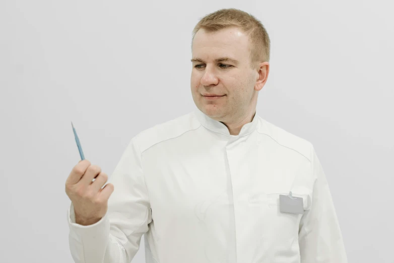 a man in white wearing a chef uniform with scissors