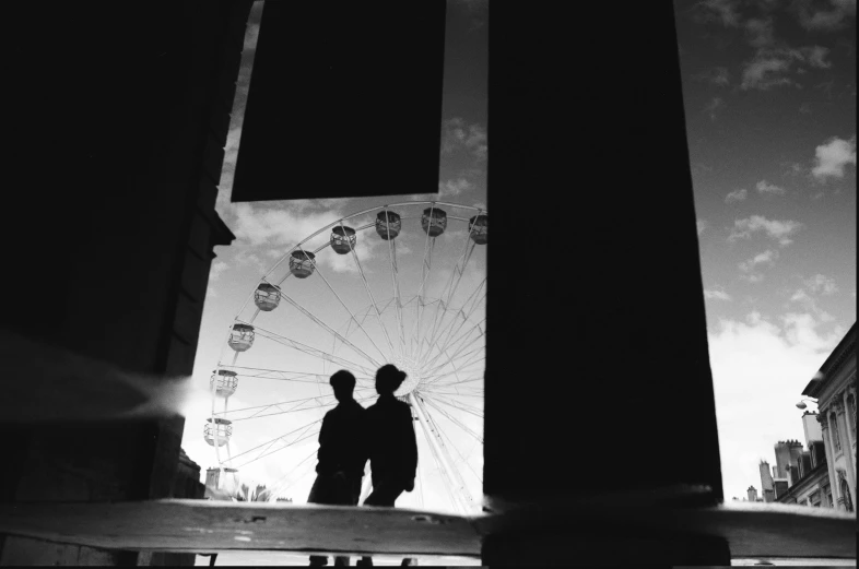 a man and woman standing in front of a ferris wheel