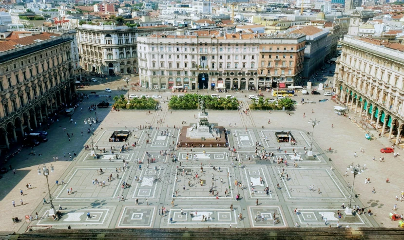 people gather around an outdoor fountain in a large city