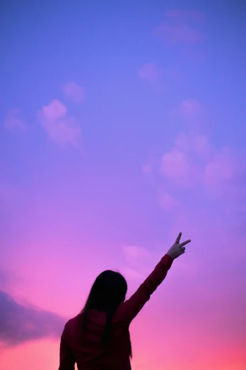 a girl in silhouette waving to a purple sky