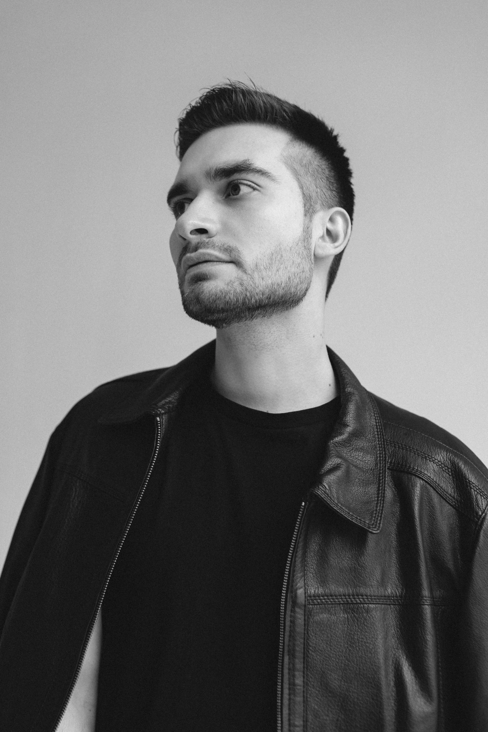 black and white portrait of a man in leather jacket looking off to the side