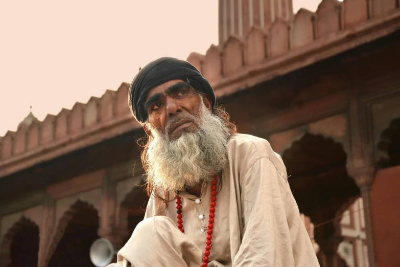 an old man with a long beard sitting in front of a building