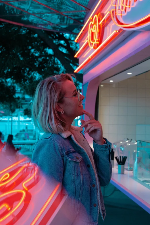 a woman standing outside a building next to neon signs