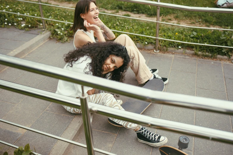 two girls are sitting on the stairs outside