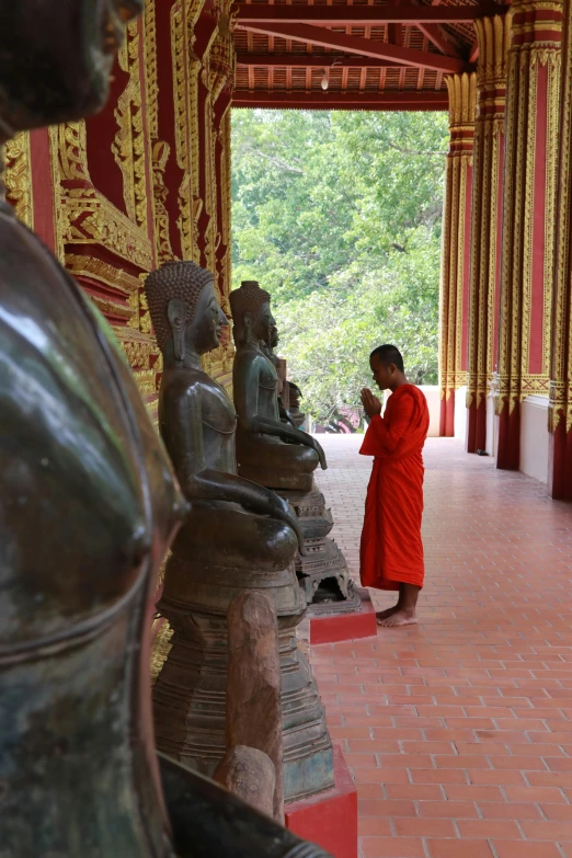 the person in a red robe is standing by statues