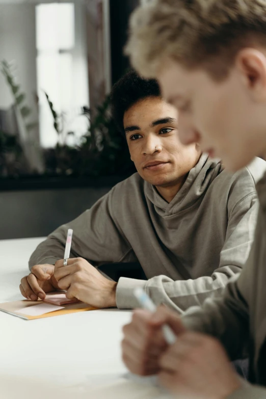 two young men at a table working together