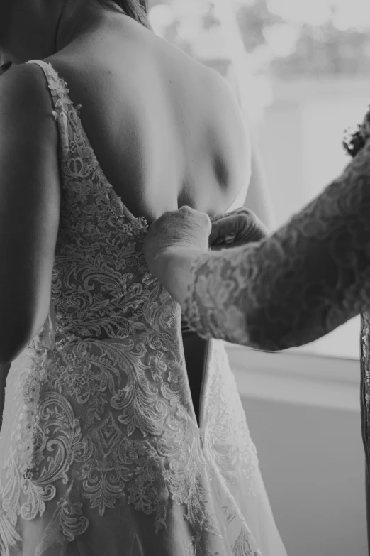 a bride is tying the strap of her wedding dress