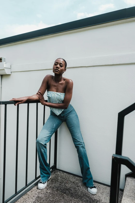 a black woman in jeans leaning against a wall