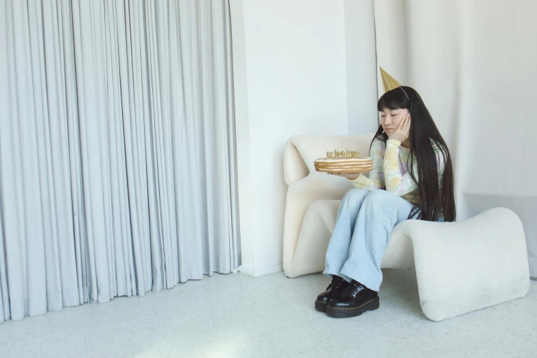 a woman sitting on a chair while holding a cake