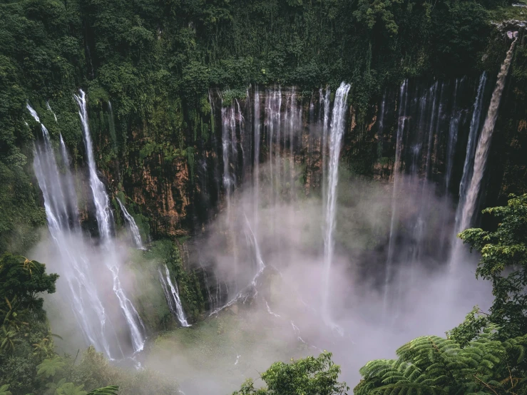 a group of waterfalls towering above a forest