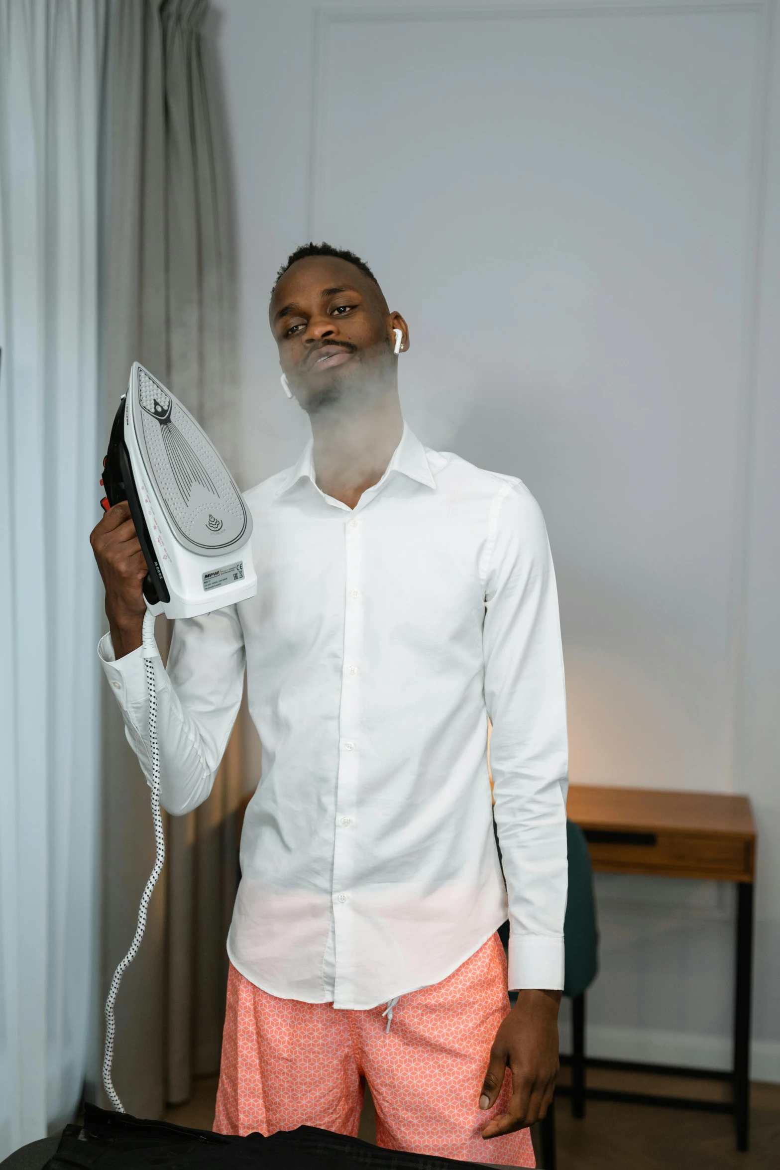 a young man smiles as he holds a device in front of his face