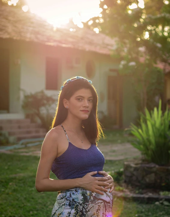 pregnant woman in yard with sun shining bright behind