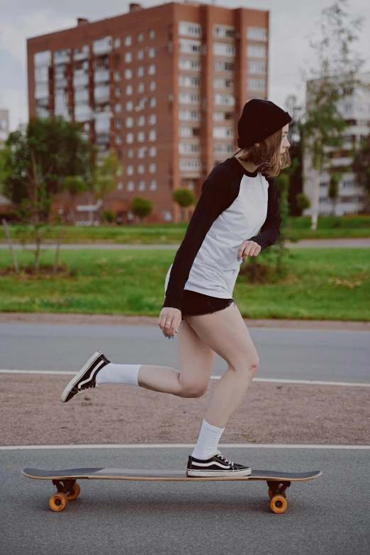a woman in short shorts and sneakers is running on a skateboard