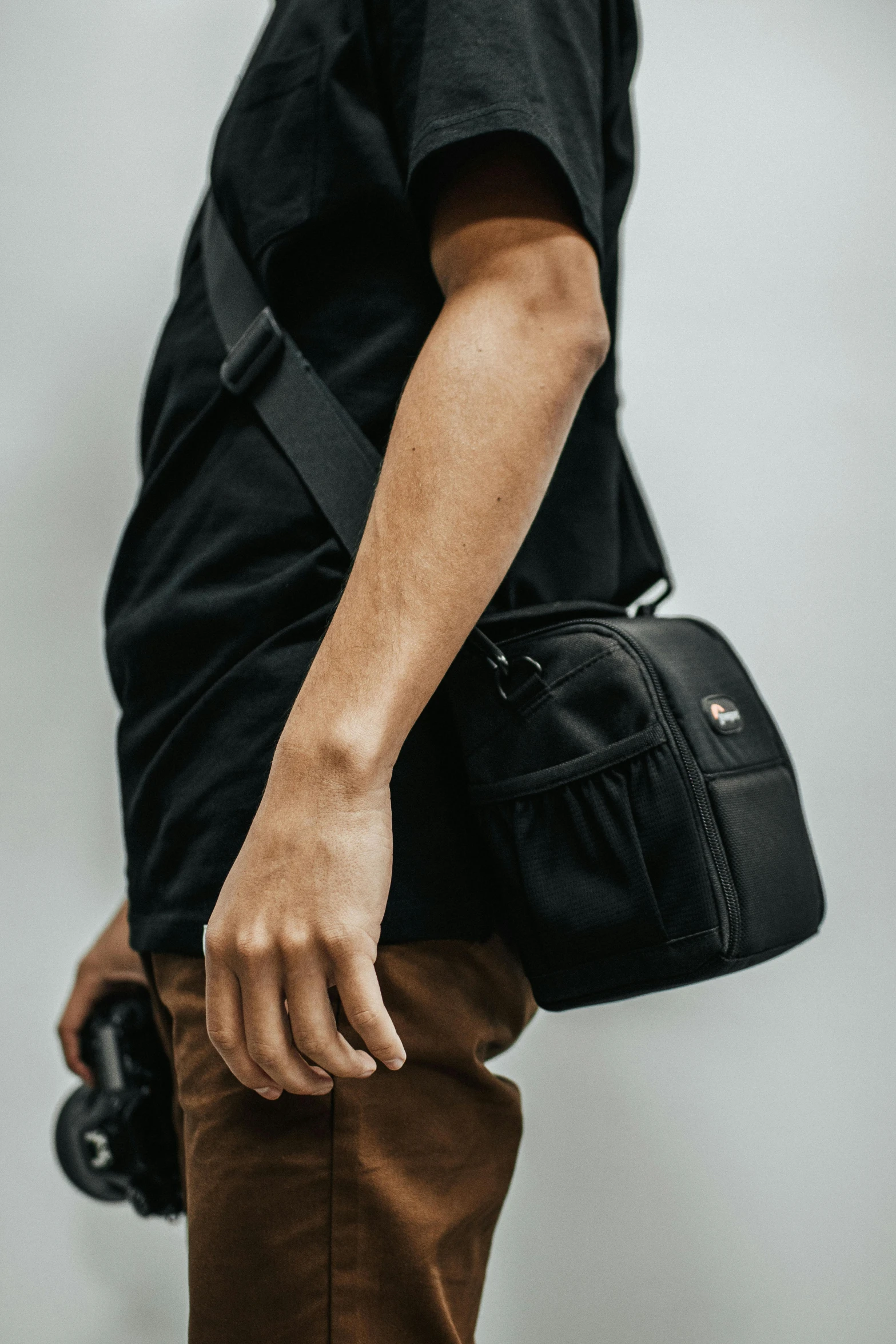 man with camera standing up and holding black bag